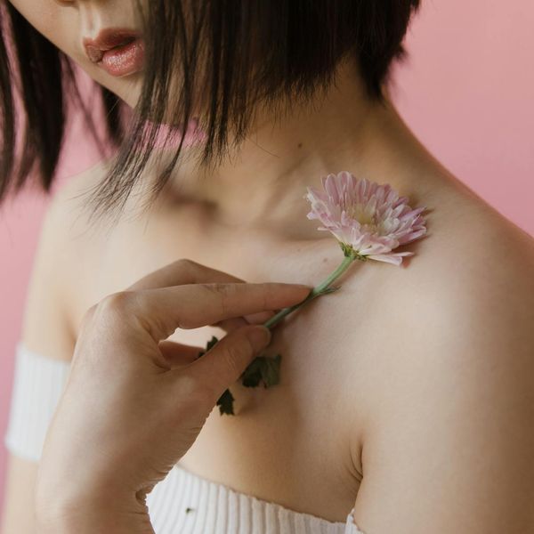 Person stretching gracefully in a minimalist setting with soft pink light.